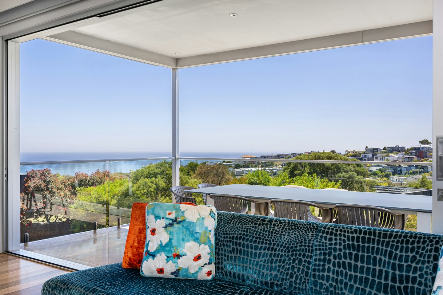 Salon moderne donnant sur un balcon et une vue sur l'océan côtier.