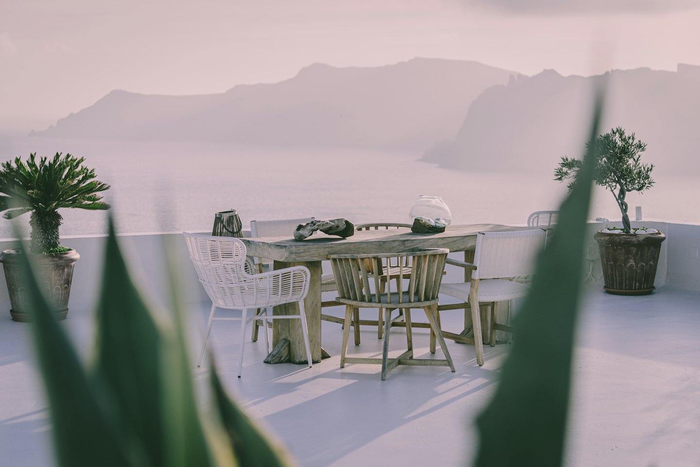 Ensemble de table et chaises en bois sur une terrasse côtière.