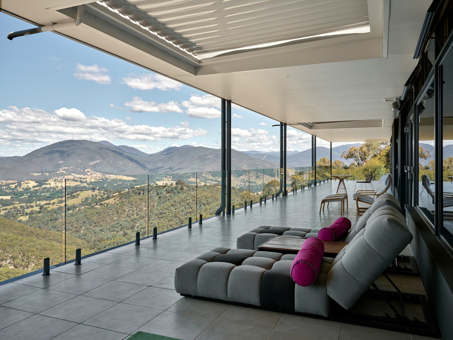 Terrasse extérieure moderne avec mobilier de salon modulable donnant sur un paysage montagneux.