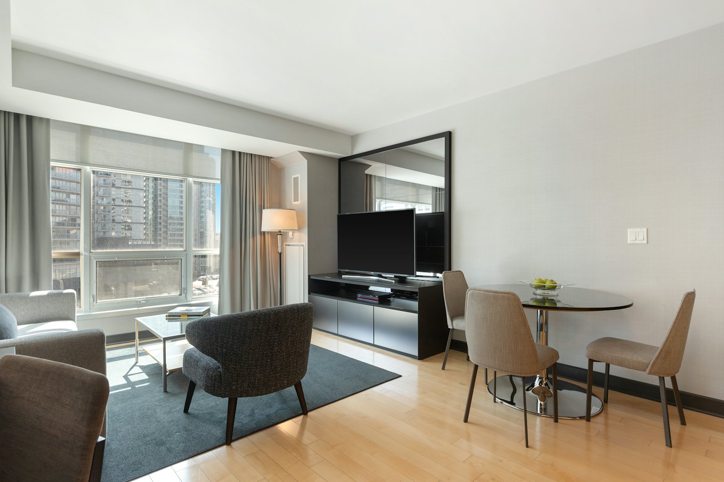 Salon d'appartement moderne avec vue sur la ville par une grande fenêtre.